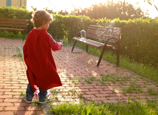 boy makes soap bubbles, soap bubble explodes, red cape child superhero, alchemist