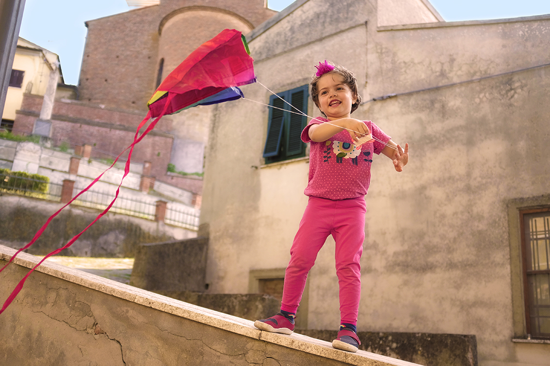 Child Standing on a wall flying a kite