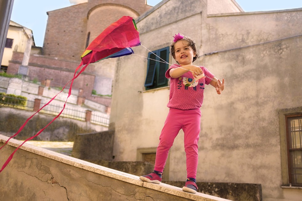 Child Standing on a wall flying a kite